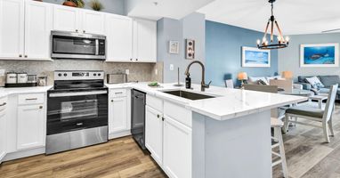 Modern kitchen w/ white cabinetry, island seating, & full-size appliances for easy meals
