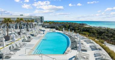 Resort-style pool surrounded by loungers & umbrellas, perfect for sunny afternoons near the water.