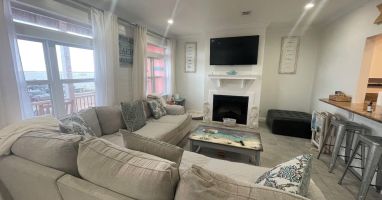Spacious living area with large comfy sectional with TV overlooking the marina