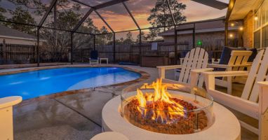 Polywood adirondack chairs around gas fire pit near private heated and screened-in pool.