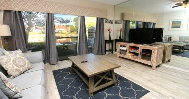 Spacious living room with large windows that let in natural light and flat screen TV