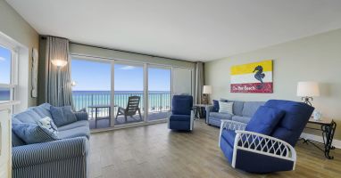 This spacious beachfront living area offers panoramic views of the Emerald Coast through large sliding glass doors, creating the perfect place to relax after a day on the beach.