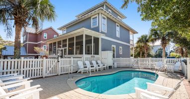 Charming coastal home with private pool surrounded by palm trees and white picket fence for your perfect beach getaway.