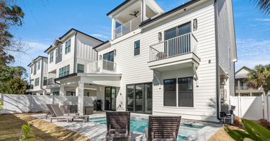 Modern multi-story vacation home with private pool, outdoor lounging area, and tropical landscaping in a peaceful neighborhood setting.