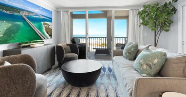 Unwind in this stylish living room where coastal artwork meets ocean views through your private balcony doors.