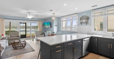 Spacious open layout with quartz countertops, navy cabinets, and lake views from the kitchen—perfect for entertaining and relaxing in style.