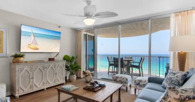 Step into your coastal living room where turquoise waters stretch endlessly beyond your private balcony. Sink into plush seating, feel the ceiling fan's gentle breeze, and unwind as ocean views frame your getaway.