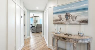 Warm coastal vibes welcome you home through this bright hallway, where beach-themed artwork and rustic furnishings create your perfect seaside retreat.