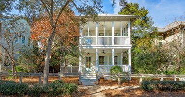 Charming Southern-style home featuring double-story wraparound porches and peaceful tree-lined street location.