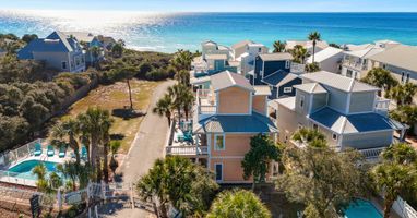 Coastal vacation rental community featuring colorful beach houses, swimming pools, and pristine turquoise waters just steps away.