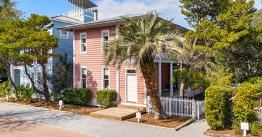 Charming coastal cottages nestled among palm trees and lush landscaping create a welcoming seaside retreat atmosphere.