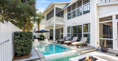 Elegant home features a private pool and fire pit surrounded by tropical landscaping for ultimate relaxation.