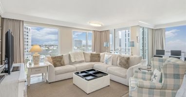 Relax in your bright living room with plush seating and stunning city views through floor-to-ceiling windows.