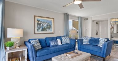 Relax in this bright coastal living space featuring comfortable seating, stylish beach-inspired décor, and easy access to the private patio overlooking the golf course. A perfect spot to unwind after a day in the sun.