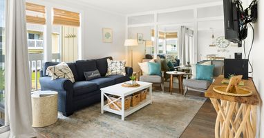 Sink into your spacious living room where coastal charm meets comfort—plush seating, warm wood accents, and abundant natural light create your perfect retreat.