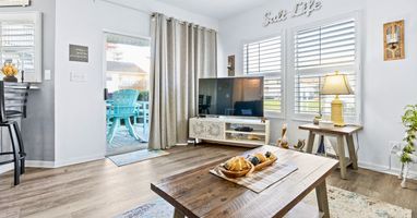 Relax in your bright living space with coastal touches, where morning light filters through plantation shutters and opens to your private patio retreat.