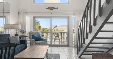 Relax in your bright coastal living room with ocean-themed touches and private balcony access.