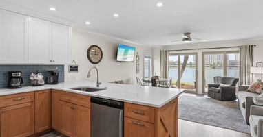 Your spacious waterfront retreat features a sleek modern kitchen flowing into a comfortable living area with stunning lake views right outside your door.