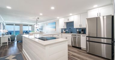 Your gourmet kitchen features sleek white cabinetry, stainless steel appliances, and a spacious island where you can cook while enjoying stunning ocean views.