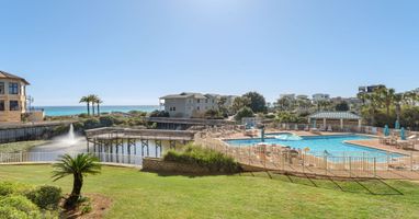 Stunning beachfront resort community with sparkling pool facilities and coastal views. Property buildings nestled among palm trees near pristine shoreline.