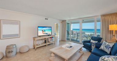Sink into plush blue sofas while enjoying stunning ocean views through floor-to-ceiling windows in your coastal retreat.