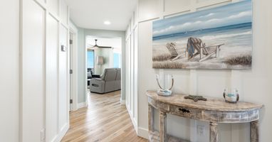 Warm coastal vibes welcome you home through this bright hallway, where beach-themed artwork and rustic furnishings create your perfect seaside retreat.
