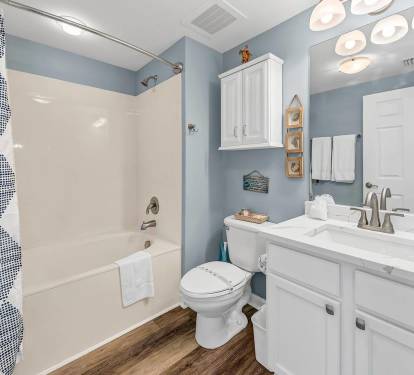 Clean, coastal-style bathroom w/ tub/shower combo, white vanity, & fresh finishes