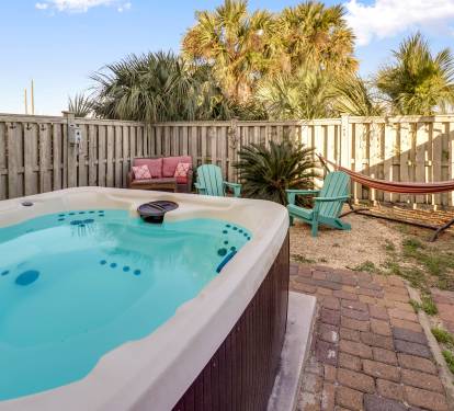 private backyard with hot tub, hammock, fire pit, and grill