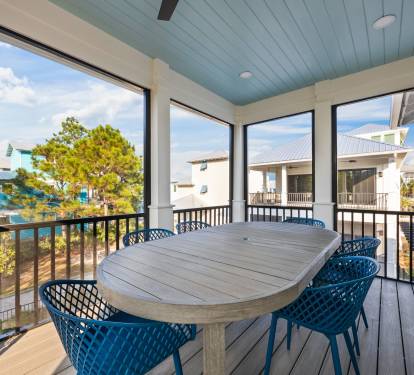 A second view of the screened upper porch shows its open, airy feel and peaceful surroundings. Enjoy dining with views of the pool and neighboring porches, where groups can easily connect and unwind together.