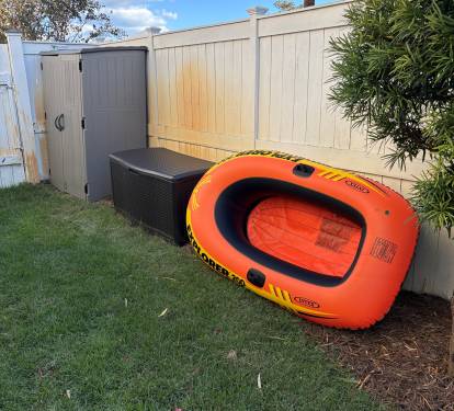 Fully fenced backyard with outdoor storage and pool accessories.