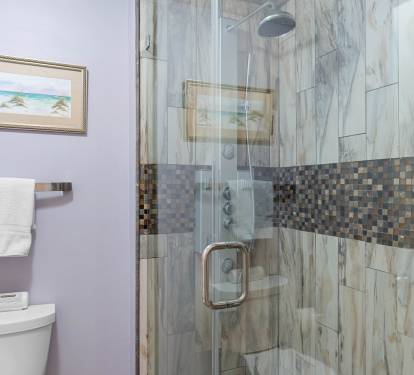 Clean bathroom setup w/ tub & shower combo, bright lighting & simple finishes.