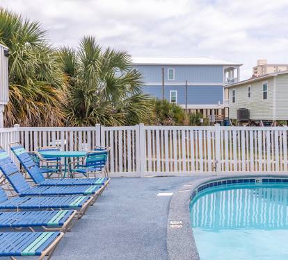 The shared pool is tucked behind fencing and palms, with loungers and tables set on a rubberized deck that’s easy on bare feet. A simple, comfortable spot to cool off or spend a quiet afternoon outdoors.