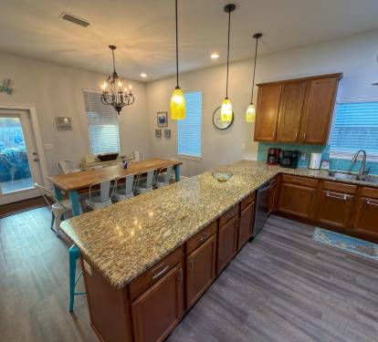 Brilliant pendant lighting, rich cabinetry, and thoughtful design details elevate the heart of the home.