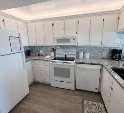 Well lit kitchen area with new appliances.