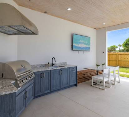 Gather outdoors with a summer kitchen, grill, smart TV, and a perfect spot for family meals.