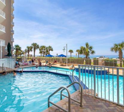 Resort-style pool w/ lounge chairs, palm trees & a relaxed spot to cool off under the sun.