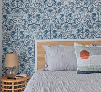 Whimsical seahorse wallpaper and a king bed dressed in soft coastal tones.