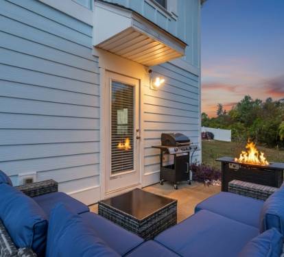 Private outdoor patio with comfortable lounge seating, fire pit table, and BBQ grill perfect for relaxing evenings, grilling meals, and enjoying quality time outdoors in a cozy setting.