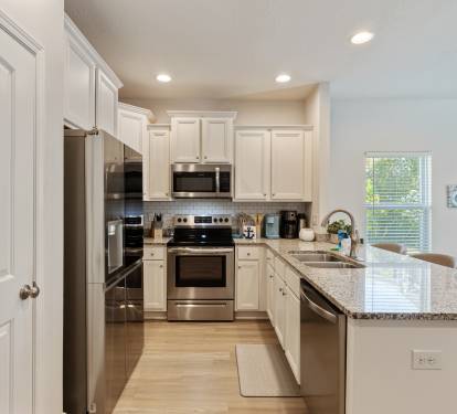 Modern, fully equipped kitchen with stainless steel appliances, granite countertops, and ample cabinet space. Bright and open layout with bar seating perfect for cooking, entertaining, or enjoying meals together during your stay.