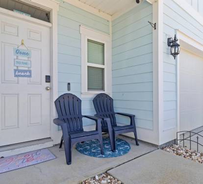 Charming front entry with coastal d&eacute;cor and a cozy seating area. Enjoy a welcoming porch with two chairs perfect for morning coffee or relaxing before heading out to explore the beach and nearby attractions.