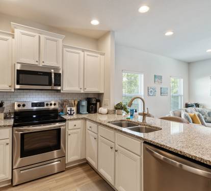 Modern, fully equipped kitchen with stainless steel appliances, granite countertops, and ample cabinet space. Bright and open layout with bar seating perfect for cooking, entertaining, or enjoying meals together during your stay.