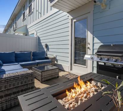 Private outdoor patio with comfortable lounge seating, fire pit table, and BBQ grill perfect for relaxing evenings, grilling meals, and enjoying quality time outdoors in a cozy setting.