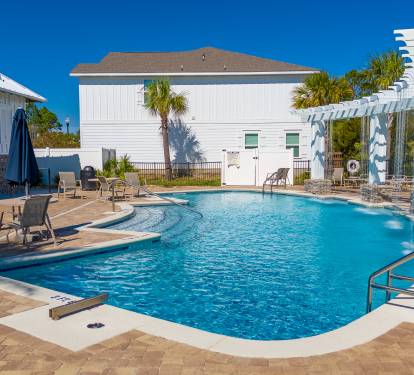 Resort-style community pool with plenty of lounge chairs and shaded seating. 