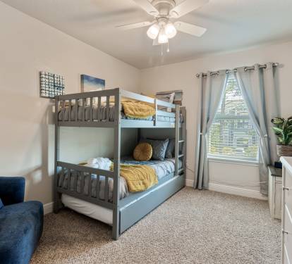 Spacious bunk room perfect for families and kids, featuring cozy beds, soft linens, and a wall-mounted TV. Bright natural light, comfortable seating, and playful d&eacute;cor create a fun and relaxing space for everyone.