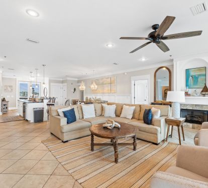 Relax in an elegant coastal living room featuring designer furnishings, expansive windows, and Gulf views. A perfect blend of comfort and style, designed for families who want more than just a rental.