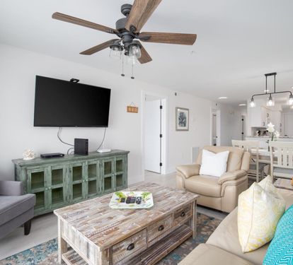 Living Room with Breathtaking Views Relax in this stylish living area, featuring plush seating, coastal decor, and a large flat-screen TV. The sliding glass doors lead to your private balcony, showcasing uninterrupted views of the sparkling Gulf waters. P