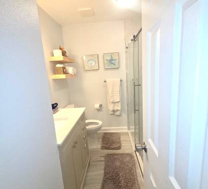 New Shower, comfort height toilet and vanity. Modern. Blow dryer, shampoo, and shower gel.