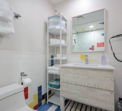 Convenient downstairs full bath with modern walk-in shower, vibrant tile accents, and signature blue-and-white striped flooring.