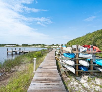 Wooden boardwalk leads to serene lake with kayaks and canoes available for rental at this waterfront property.