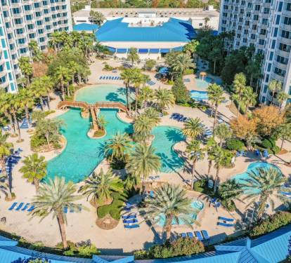 Elevated view over the resort grounds showing pools, buildings, and lush landscaping below.